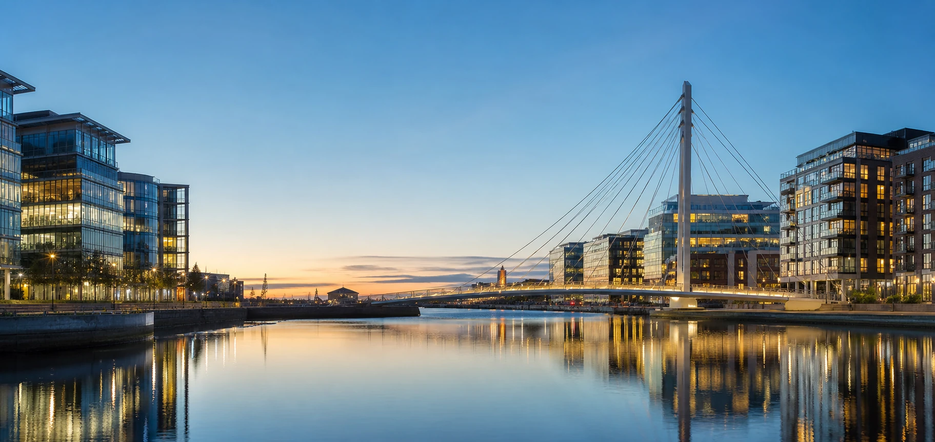 Modern waterfront district and cable-stayed bridge at dusk